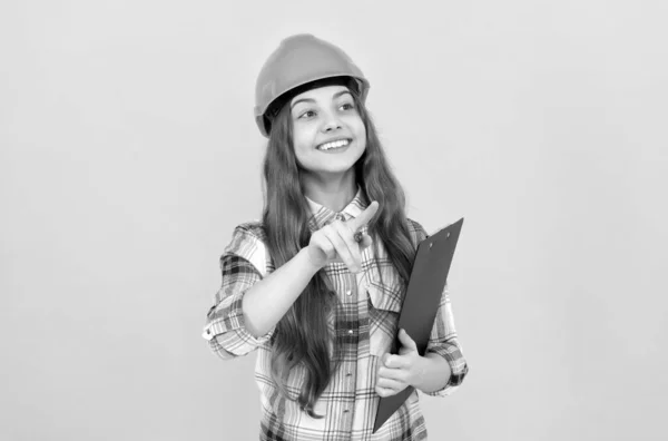 Menina adolescente feliz no capacete e camisa quadriculada fazendo notas na área de transferência, ocupado — Fotografia de Stock
