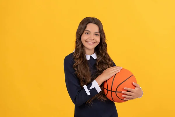 Felice bambino tenere palla da basket su sfondo giallo, torna a scuola — Foto Stock