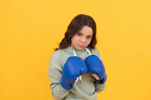 Ernstes Kinderporträt in Boxhandschuhen auf gelbem Hintergrund — Stockfoto