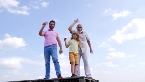 Щаслива сім'я хлопчика-син і дідусь тримають паперові літаки стоячи високо в небі, свобода — стокове відео