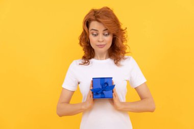 Sarı arka planda hediye kutusu olan pozitif kız, alışveriş.