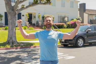 Bağıran adam araba ve evin yanında duruyor.