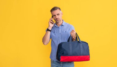 İş adamı akıllı telefondan seyahat çantasıyla konuşur. Adamın sohbet çantası var..