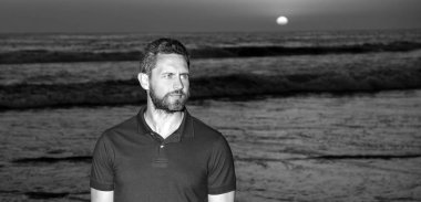 Gündoğumu plajındaki beyaz adam. Gömlekli sakallı adam. Yaz modası.