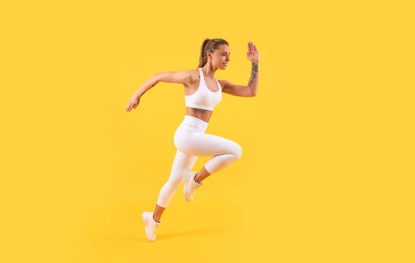 Chica de fitness corredor corriendo en ropa deportiva sobre fondo amarillo —  Fotos de Stock