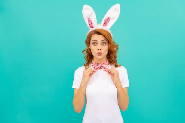 Tavşan kulaklı mutlu Paskalya kızı ve mavi arka planda papyon.