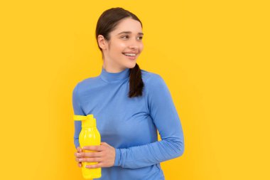 Mutlu genç bir kadın elinde su ve susuzlukla spor şişesi tutuyor.