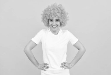 Süslü görünüşlü neşeli kız sarı arka planda turuncu peruk takıyor, parti eğlencesi