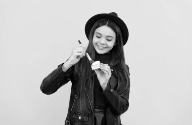 Şapkalı çocuk sarı arka plana pudra sür, makyaj yap.