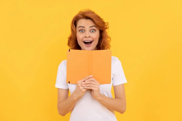 Meghökkent lány hold copybook sárga háttér, iskola — Stock Fotó