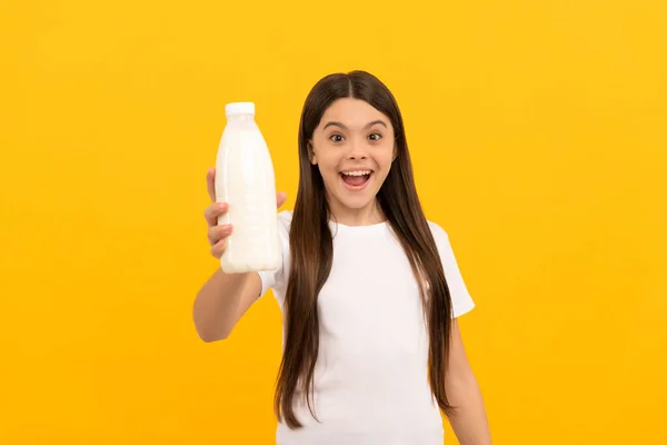 Şaşırmış çocuk süt ürünleri sunuyor. Genç kız süt içecek.. — Stok fotoğraf
