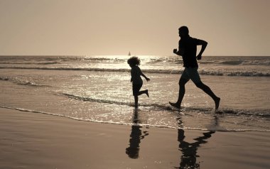Okyanusta ya da denizde çocuk silueti olan bir baba. Hafta sonu aile günü. Baba ve çocuk eğleniyor.