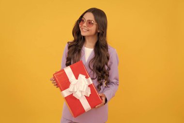 Ceketli ve gözlüklü şık bir genç kız hediye kutusu tutuyor. alışveriş zamanı.