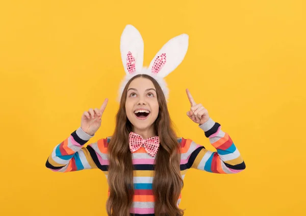 Fröhliches Osterkind in Hasenohren und Fliege auf gelbem Hintergrund. Mit Idee inspiriert — Stockfoto