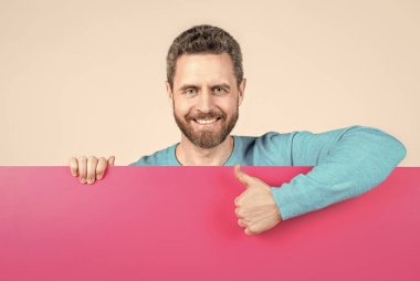 İş teklifi için fotokopi alanı olan boş pankartın arkasındaki mutlu adam başparmağını kaldır, teklif et.