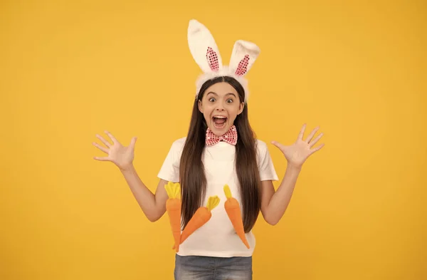 Verrast Pasen kind meisje in konijnenoren en strikje houden wortel, gelukkig Pasen — Stockfoto
