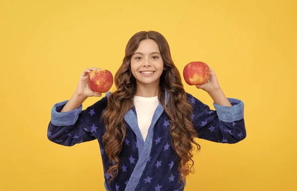 Vrolijk tiener meisje met krullend haar in comfortabele pyjama gaan naar gezonde appel eten, vitamine — Stockfoto