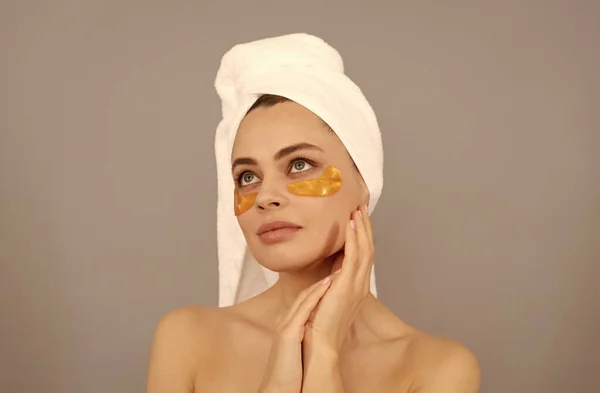 Belle fille avec une serviette éponge utiliser un bandeau facial doré pour la peau, la beauté — Photo