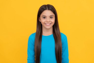 Sarı arka planda uzun saçlı neşeli genç kız, moda.