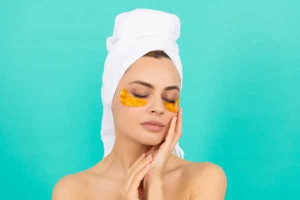 Young lady has collagen gold eye patches on face with towel — Stock Photo, Image