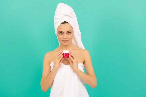 Mooie vrouw in handdoek met huid crème op blauwe achtergrond — Stockfoto