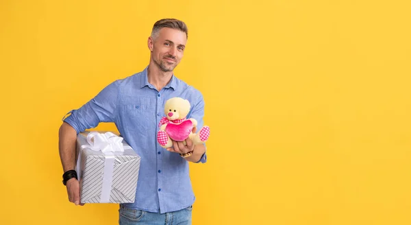 Hombre sosteniendo juguete. hombre guapo prepararse para la cita romántica. chico alegre con saludo de ocasión —  Fotos de Stock