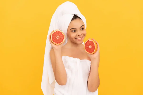 Щаслива дитина в рушнику з грейпфрутом на жовтому фоні — стокове фото