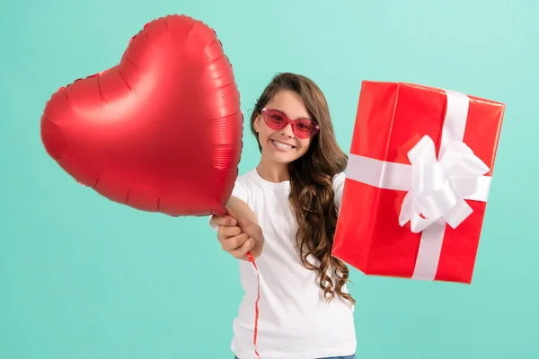 Χαρούμενη έφηβος κορίτσι με γυαλιά ηλίου δίνοντας κουτί δώρου και Ημέρα του Αγίου Βαλεντίνου κόμμα μπαλόνι καρδιά, Αγίου Βαλεντίνου — Φωτογραφία Αρχείου