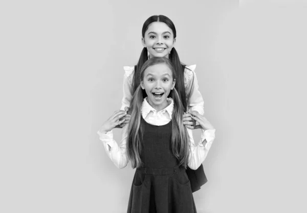 Felices amigos de la escuela abrazan en uniformes formales fondo amarillo, amistad —  Fotos de Stock