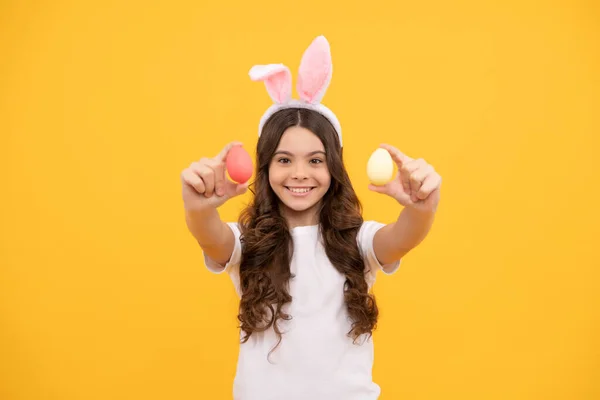 Uśmiechnięty dzieciak w króliczych uszach trzyma jajka na żółtym tle, Wielkanoc — Zdjęcie stockowe