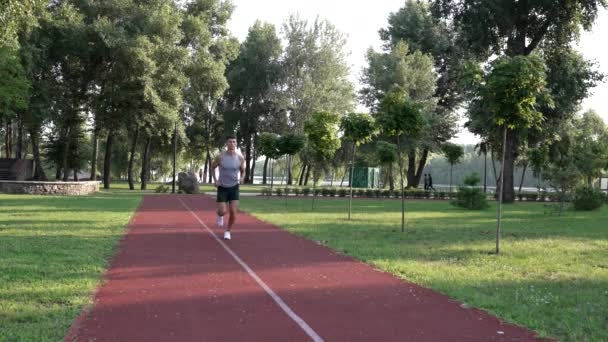 年轻的肌肉运动员在公园的跑道上跑步，运动 — 图库视频影像