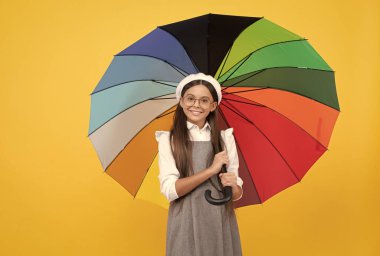 Sonbahar mevsiminde yağmur koruması için renkli şemsiyeler altında gözlüklü mutlu genç kız, iyimser..