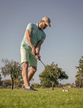 Yeşil çimlerin üzerinde golf oynayan ayakta duran adam, golf oynuyor.