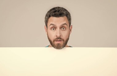 Siyah kağıdın arkasında hayretler içinde bir erkek. Reklam için kopya alanı olan şaşırmış bir adam..