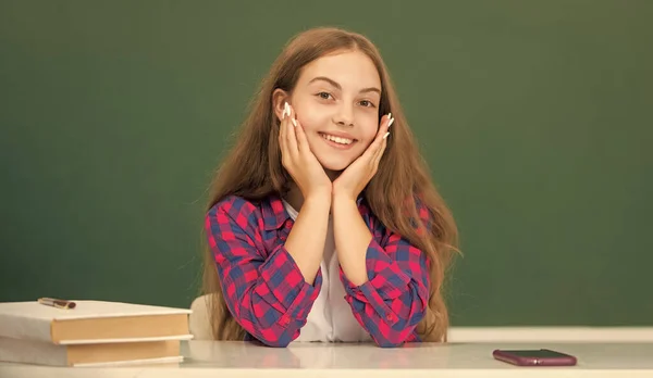 Šťastný dítě sedět ve škole na tabuli pozadí, den znalostí — Stock fotografie