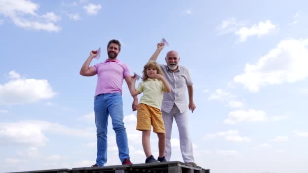 Šťastná rodina chlapečka s otcem a dědečkem drží papírová letadla vysoko, volný čas — Stock video