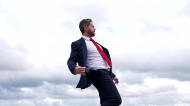 Başarılı takım elbiseli patron bulutlu gökyüzünde dans ediyor, özgürlük.