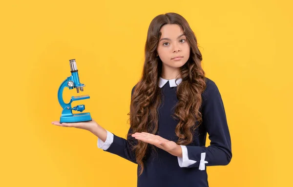Serious nerd child presenting microscope for school education on yellow background, scientist — Stock Photo, Image