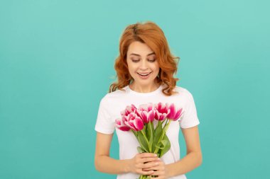 Mavi arka planda lale çiçeği buketi olan gülümseyen kadın.