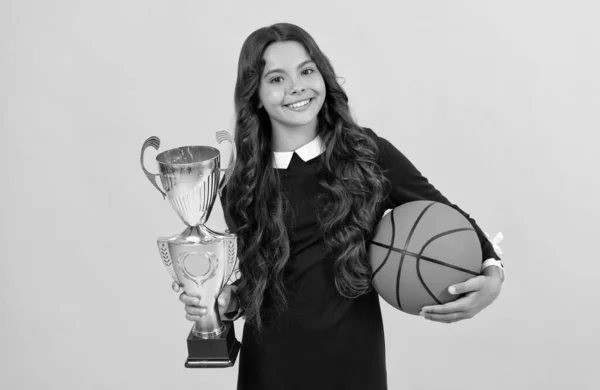 Feliz adolescente chica hold baloncesto bola y campeón taza en amarillo fondo, campeón —  Fotos de Stock