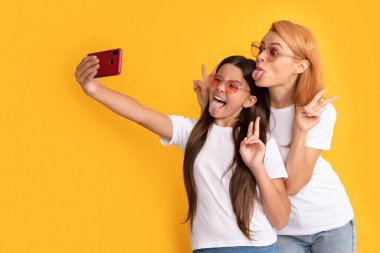 Mutlu anne ve çocuk akıllı telefondan selfie çekiyor. Barışı gösteriyor, blog yazarı.