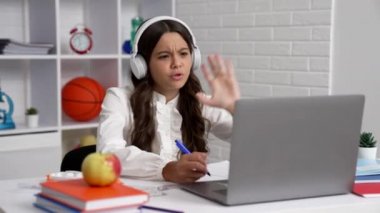 Üniformalı ve kulaklıklı liseli kız dizüstü bilgisayar eğitimi alıp okula geri dönüyor..