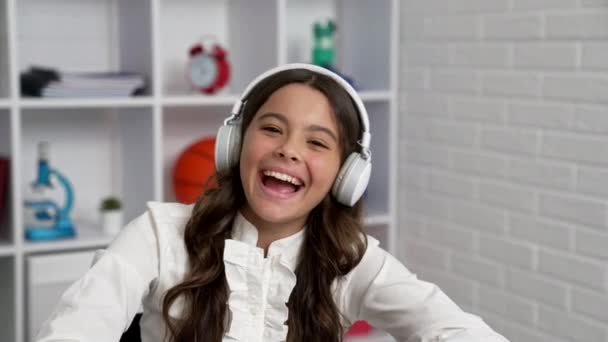 Śmiejący się dzieciak w mundurze szkolnym i słuchawki bezprzewodowe, żart — Wideo stockowe
