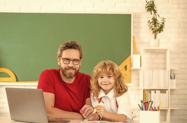 baba ve çocuk sınıfta bilgisayar ve bilgiyle çalışıyorlar.