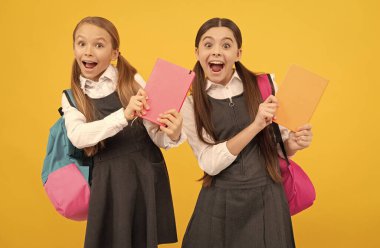 Resmi okul üniformalı mutlu çocuklar çalışma kitaplarını sarı arka plan, bilgi günü tutarlar.