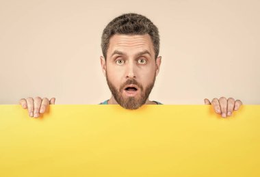 Pazarlama tasarımı ve tanıtım için fotokopi alanı olan boş sarı pankartın arkasında sakallı bir adam var..