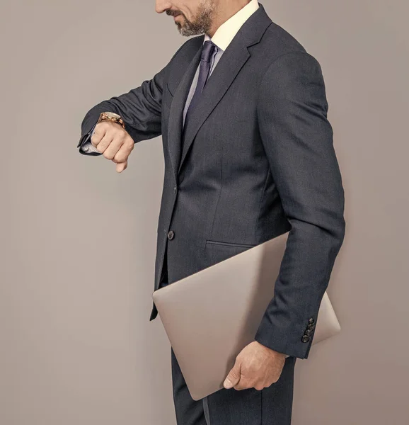 Hombre de negocios seguro en traje de negocios celebrar portátil cheking tiempo, gestión del tiempo —  Fotos de Stock