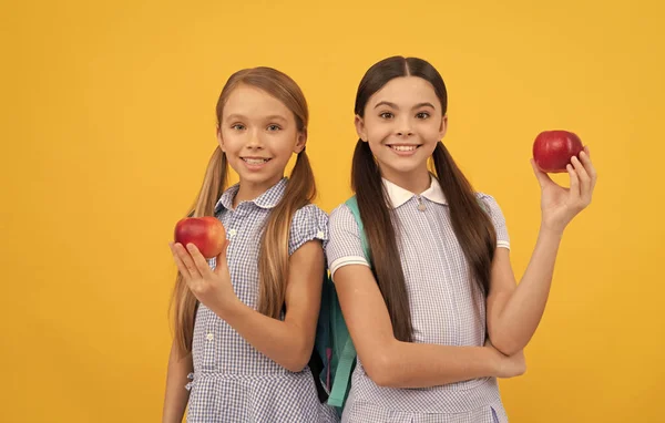 Feliz primaria niños sostienen sabrosas manzanas fruta amarillo fondo, merienda escolar —  Fotos de Stock
