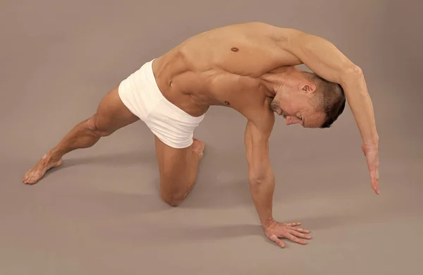 Athletic yogi man do side body stretch sidebending joga pozować szare tło, trening — Zdjęcie stockowe