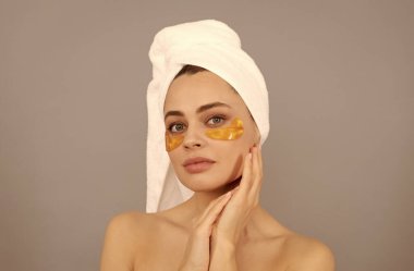 Terry havlusu olan şehvetli kadın cilt için altın göz bandı kullanır.